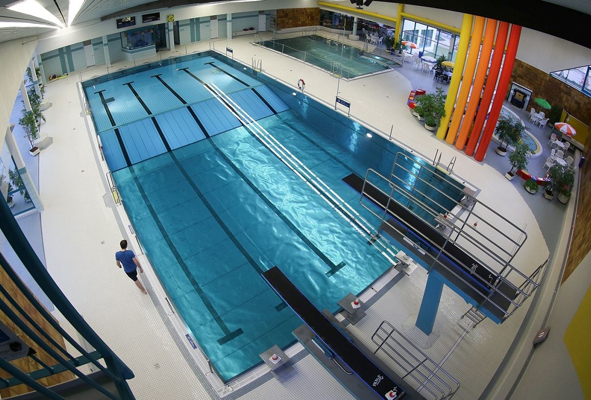 Vogelperspektive des Gronauer Hallenbads, die zwei Sprungbretter und ein großes Schwimmbecken zeigt.