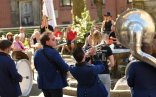 Eine Gruppe von Leuten, die mit dem Rücken zur Kamera stehen. Einige von ihnen halten ein Instrument, wie z.B. eine Trompete und eine Tuba. Eine Gruppe von Leuten, die mit dem Rücken zur Kamera stehen. Einige von ihnen halten ein Instrument, wie z.B. eine Trompete und eine Tuba.