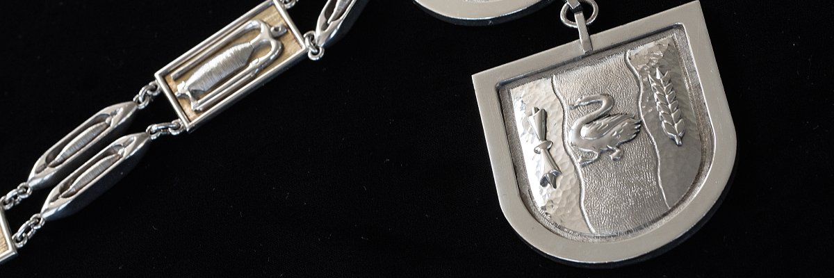 Ein Teil der silbernen Kette, die dem neuen Bürgermeister bzw. der neuen Bürgermeisterin bei Amtsantritt symbolisch umgehangen wird. Auf dem Ausschnitt ist das Wappen der Stadt Gronau eingestanzt.