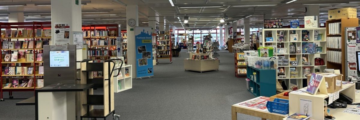 Eingangsbereich der Stadtbücherei in Gronau mit Blick von der Eingangstür auf einige Bücherregale und der Ausleihtheke in der Front.