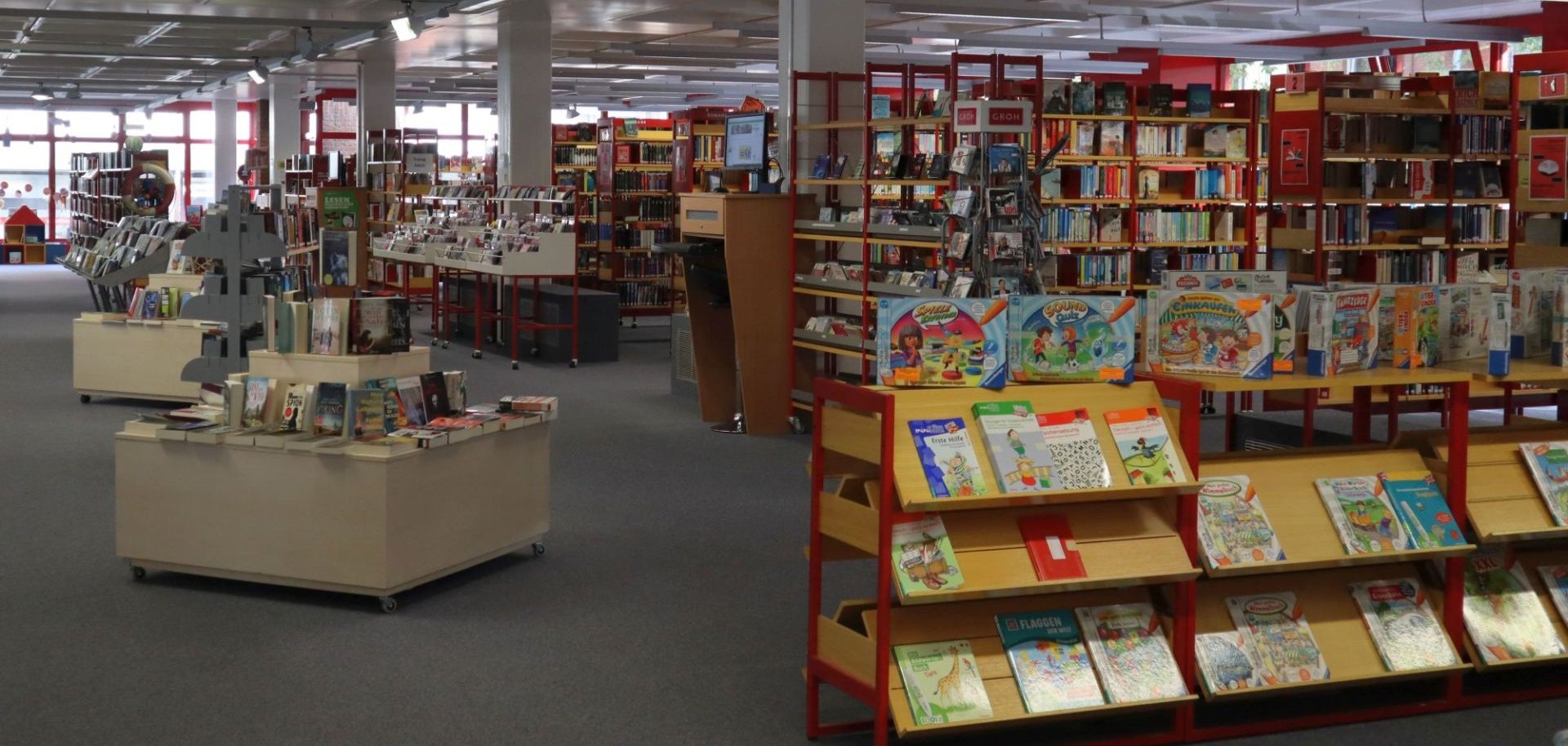 Heller Innenraum der Stadtbücherei Gronau mit Bücher- und Spieleregale.