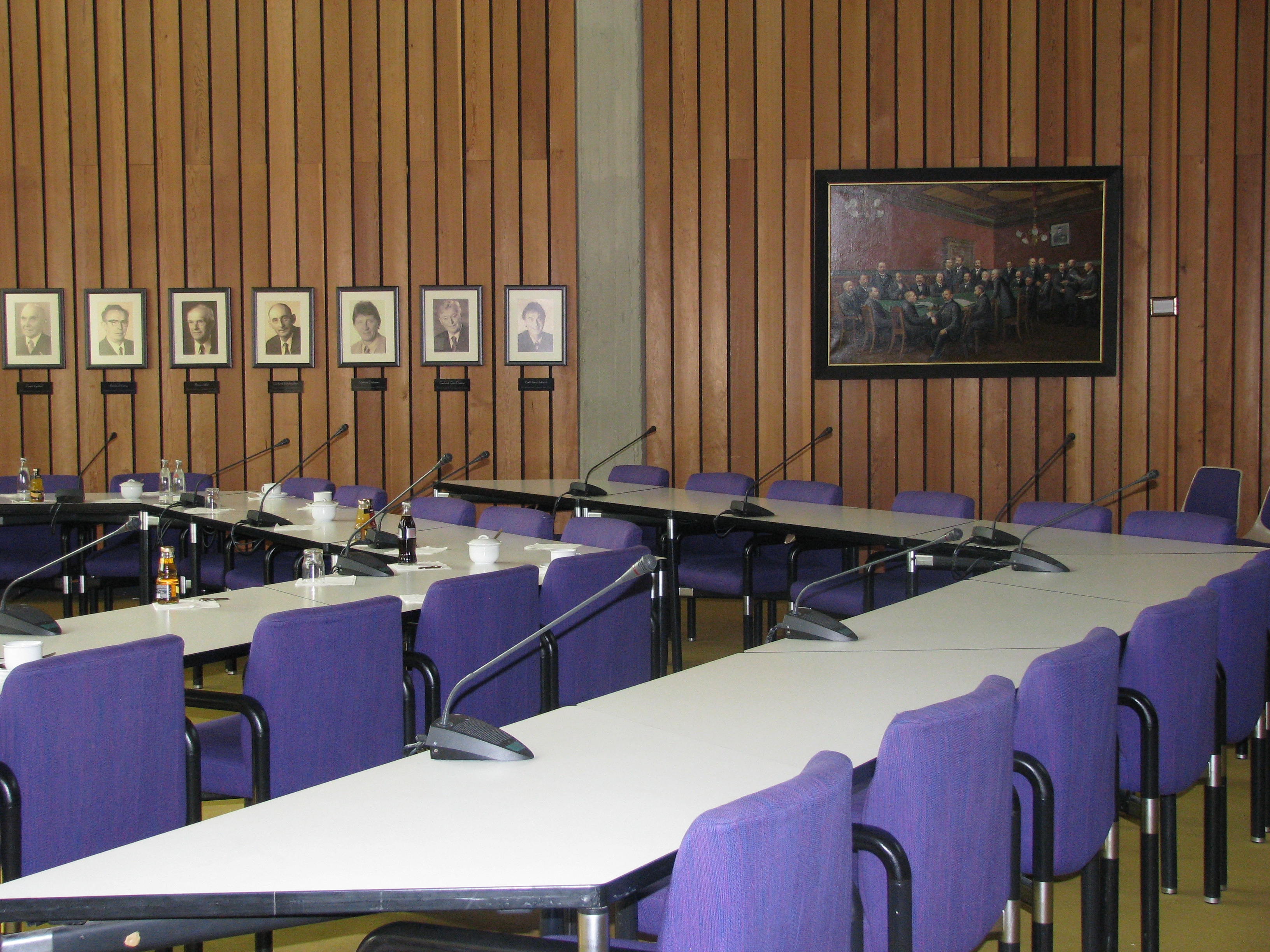 Eine Tischreihe mit Stühlen im Sitzungssaal.