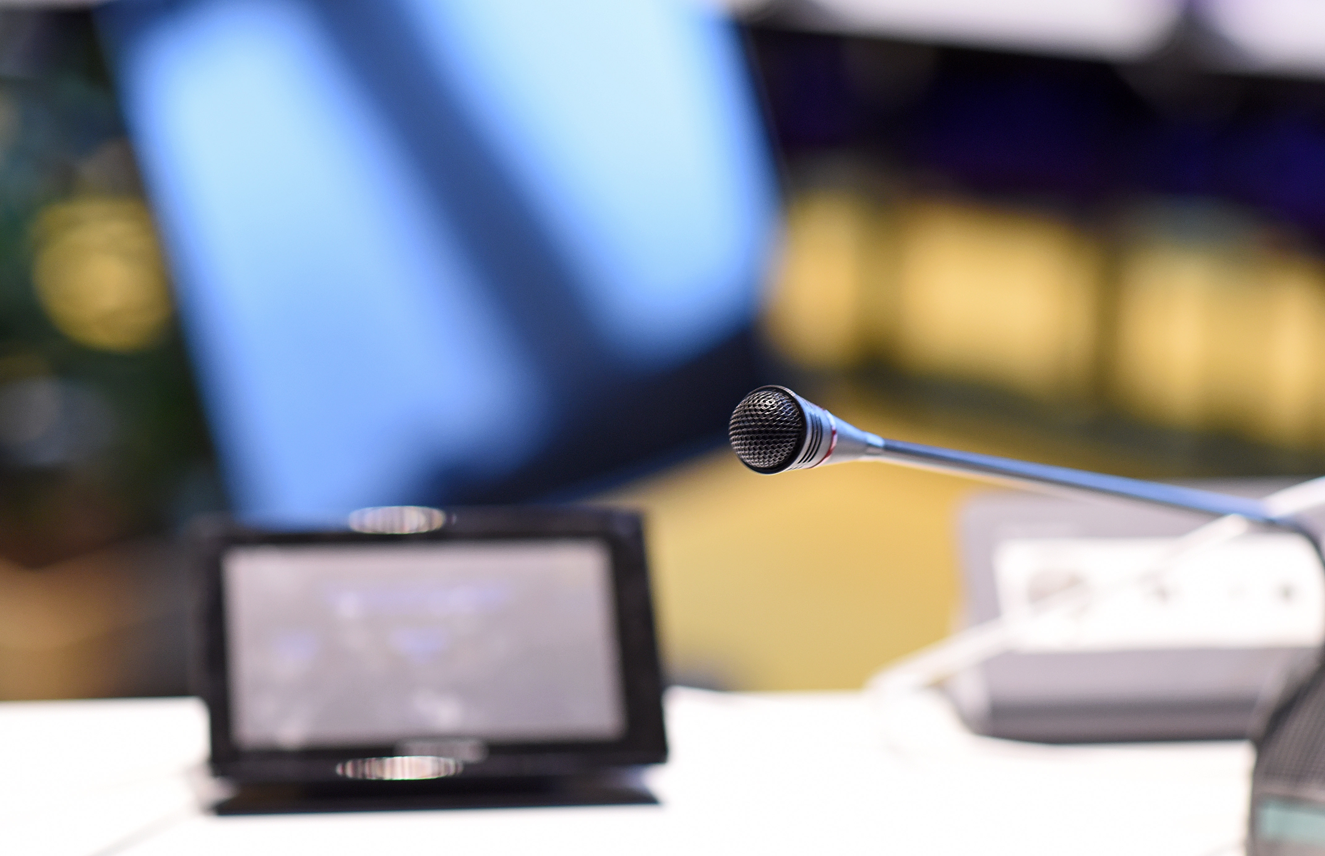 Ein Mikrofon und ein kleiner Bildschirm auf einem Tisch im Sitzungssaal.