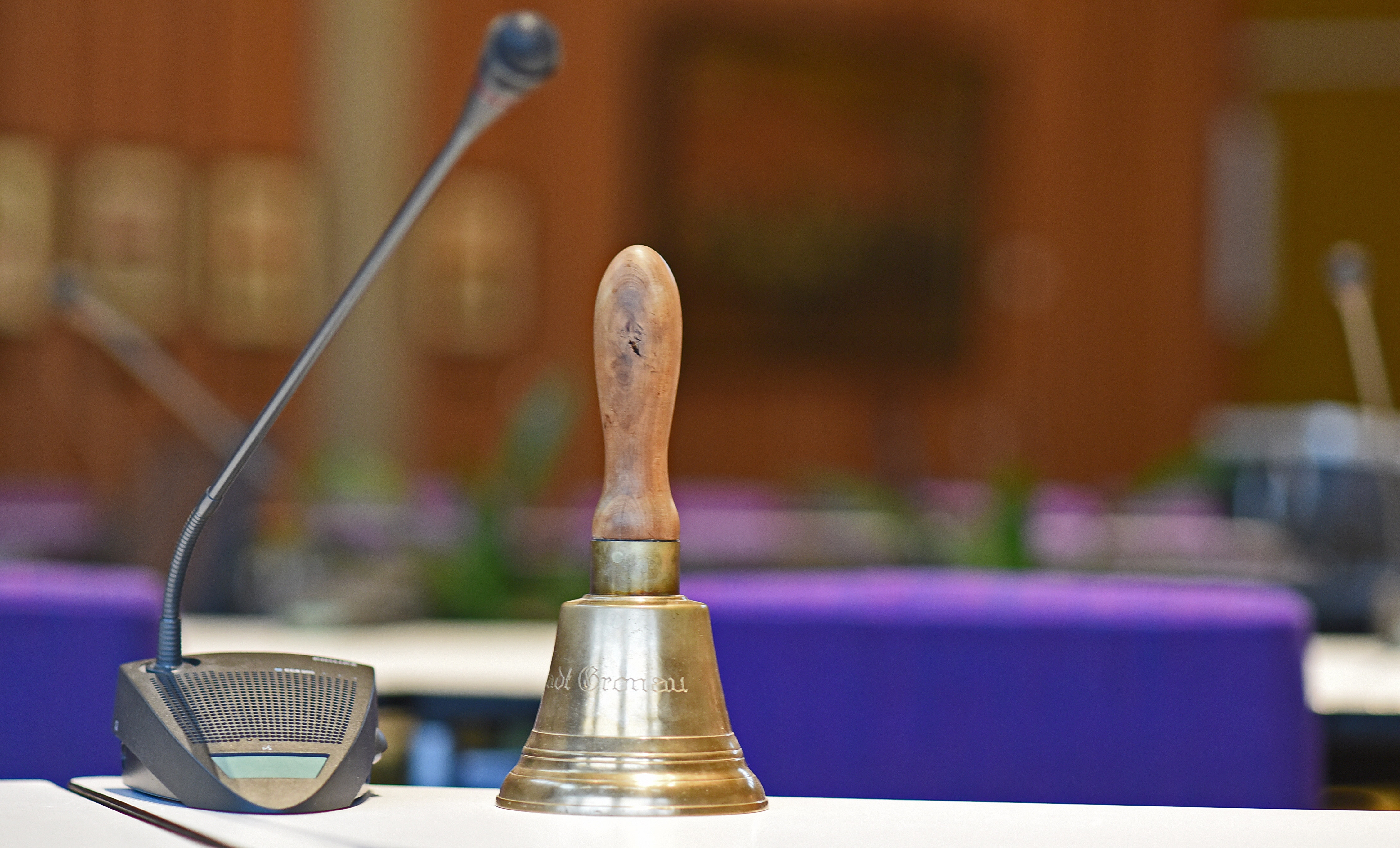 Ein Mikrofon und eine Klingel auf einem Tisch im Sitzungssaal.
