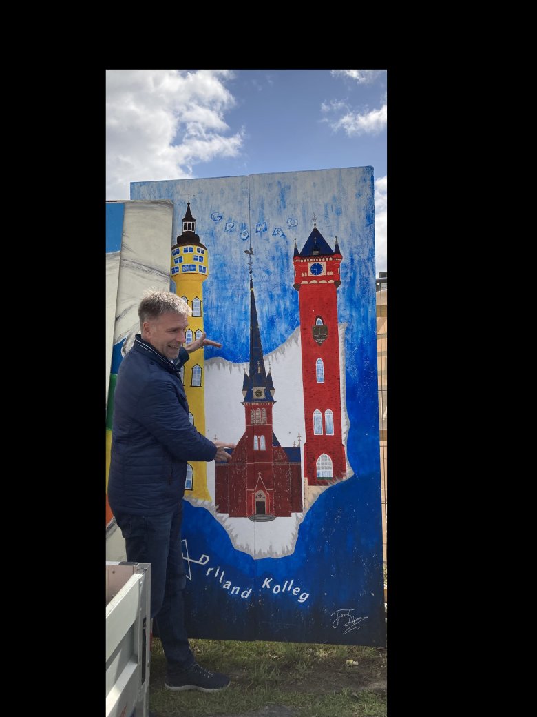 Der Bürgermeister steht vor einem Bild des Wasserturms und der kath. Kirche in Gronau