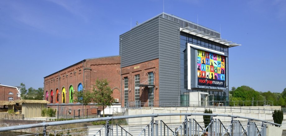 Blick auf das rock'n'popmuseum bei Tag aus Richtung der Bahnhofstraße. Links im Bild kann man das Bamboo erkennen.