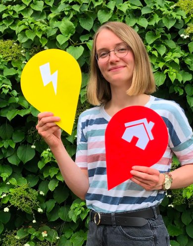 Die Klimaschutzmanagerin hält beispielhaft zwei Stecknadelmodelle hoch.