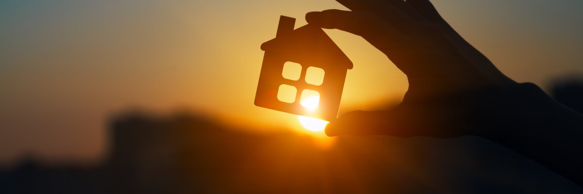 Hand hält Modell eines Hauses der Sonne entgegen