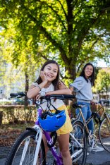 Lächelndes Mädchen lehnt auf Fahrrad Ein Mädchen stützt sich auf ihr Fahrrad und lächelt in die Kamera.