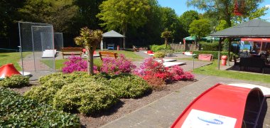 Minigolfanlage im Überblick mit blühender Begrünung und Einblick auf die Terasse der Anlage