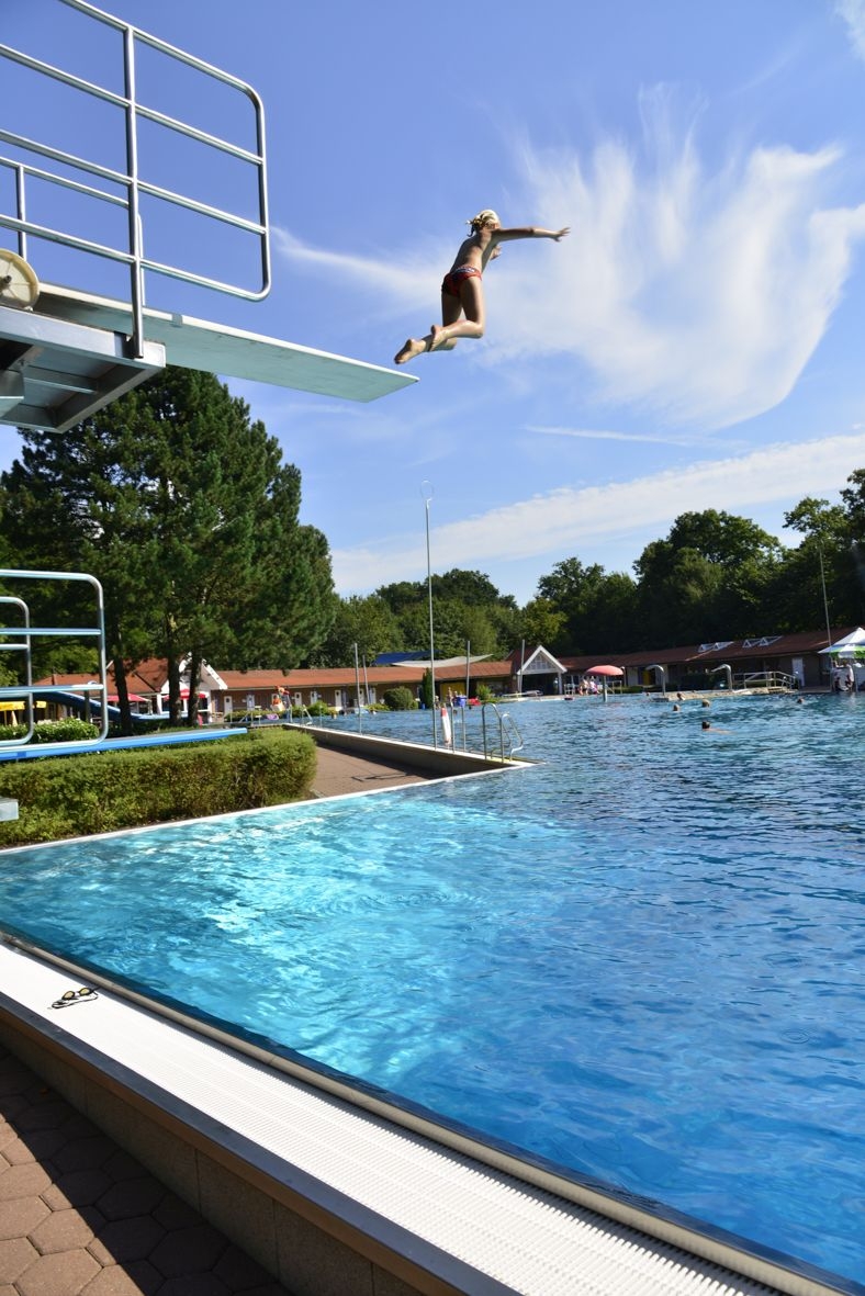 Ein Kind springt von einem Sprungbrett in ein Schwimmbecken.