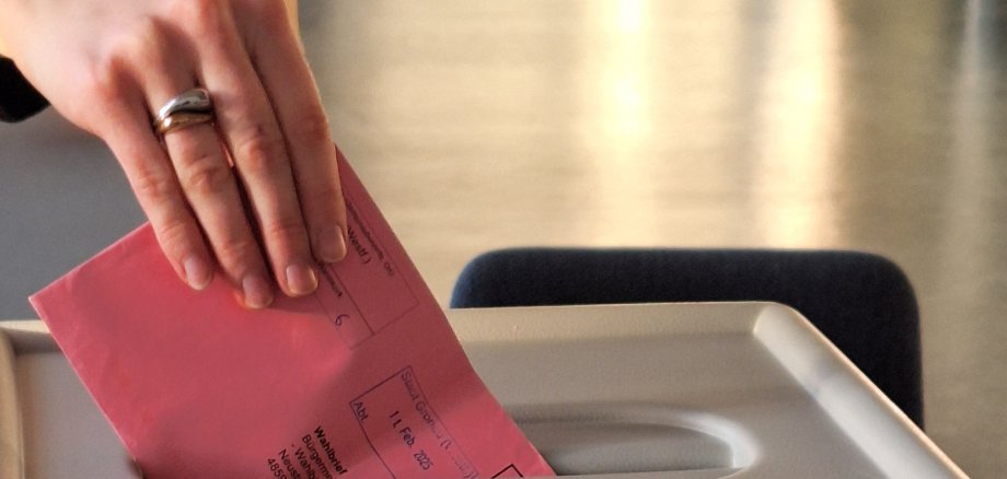 Ein Wahlbrief wird in die Wahlurne geworfen.