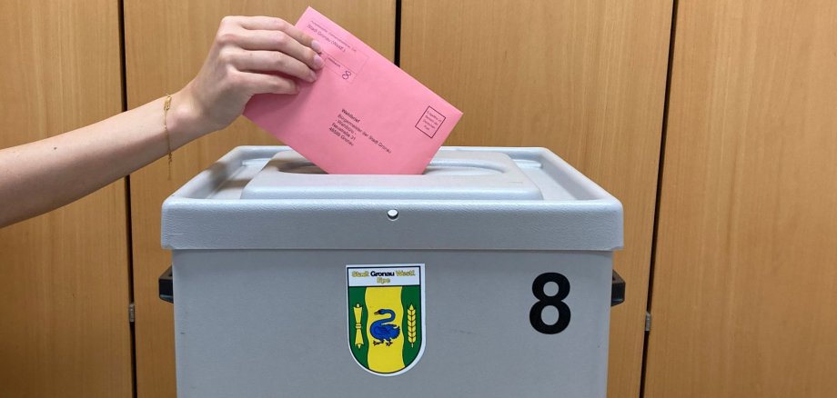 Ein Wahlzettel wird in die Wahlurne gesteckt.