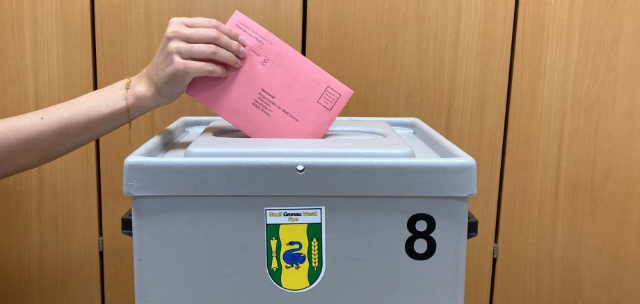 Ein Wahlzettel wird in die Wahlurne gesteckt.