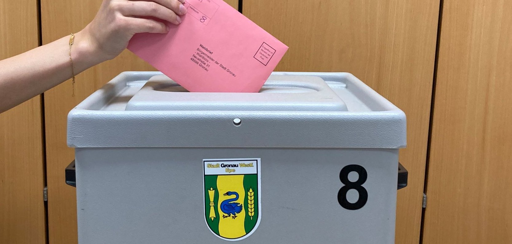 Ein Wahlzettel wird in die Wahlurne gesteckt.