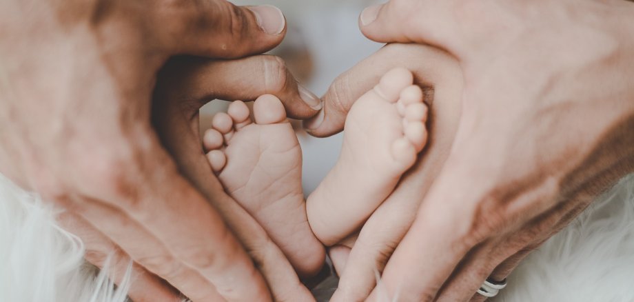 Babyfüßchen in den Händen seiner Eltern.