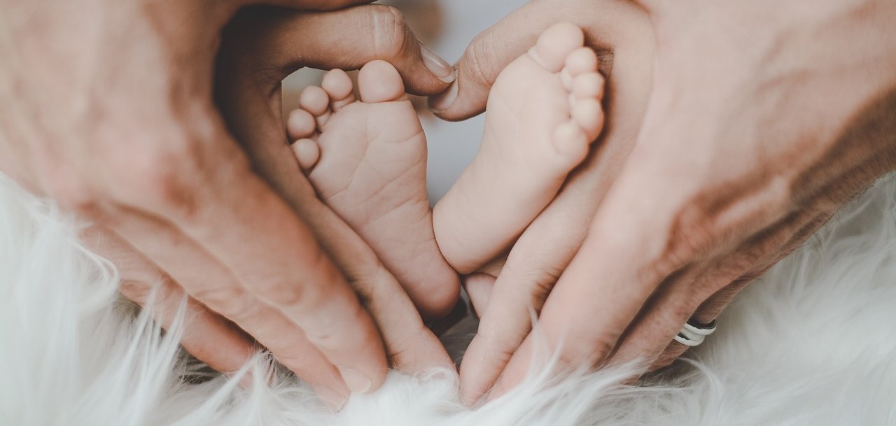 Babyfüßchen in den Händen seiner Eltern.