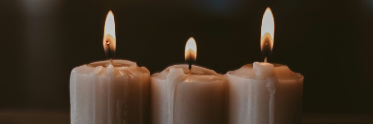 Drei weiße brennende Kerzen.