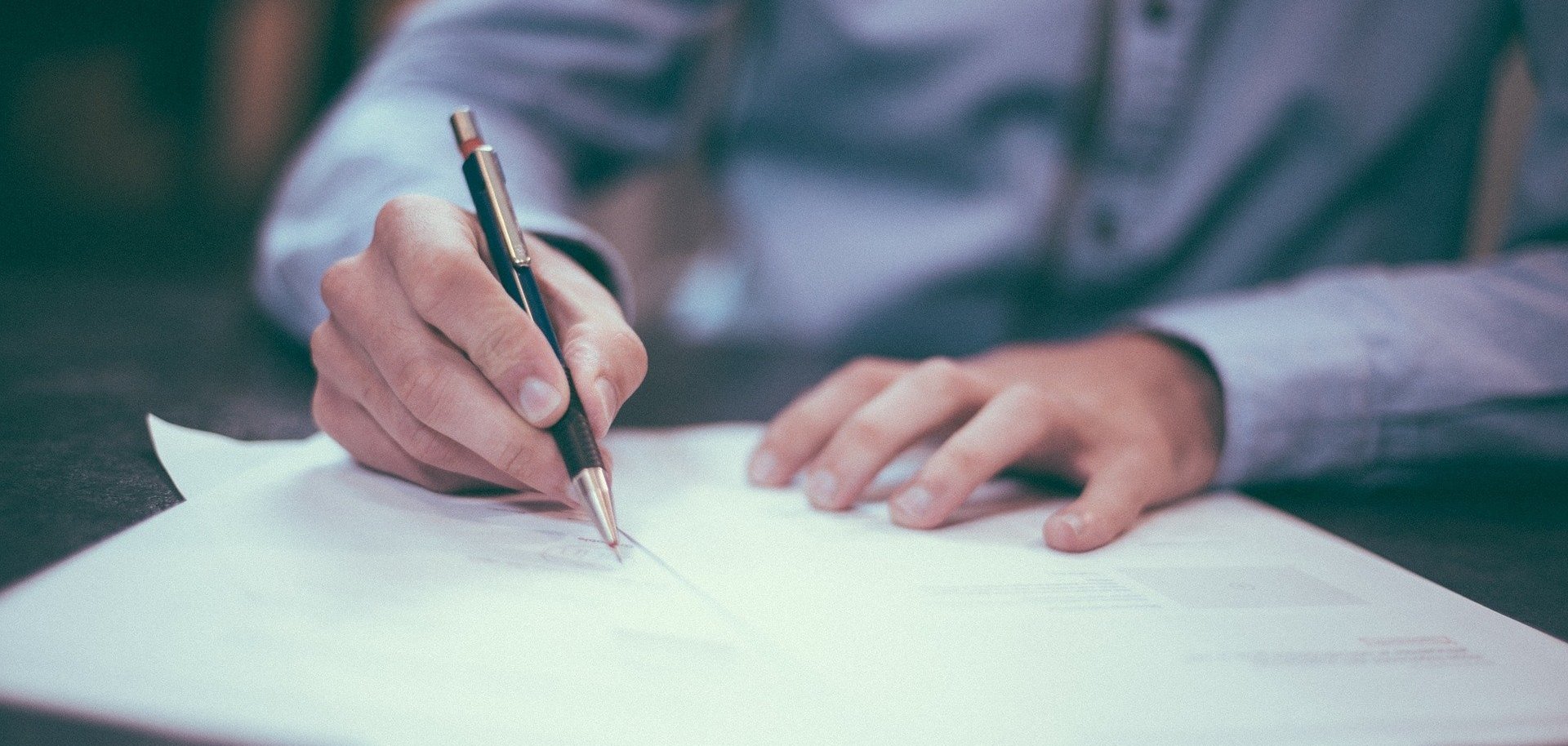 Ein Mann schreibt etwas auf ein Blatt Papier.