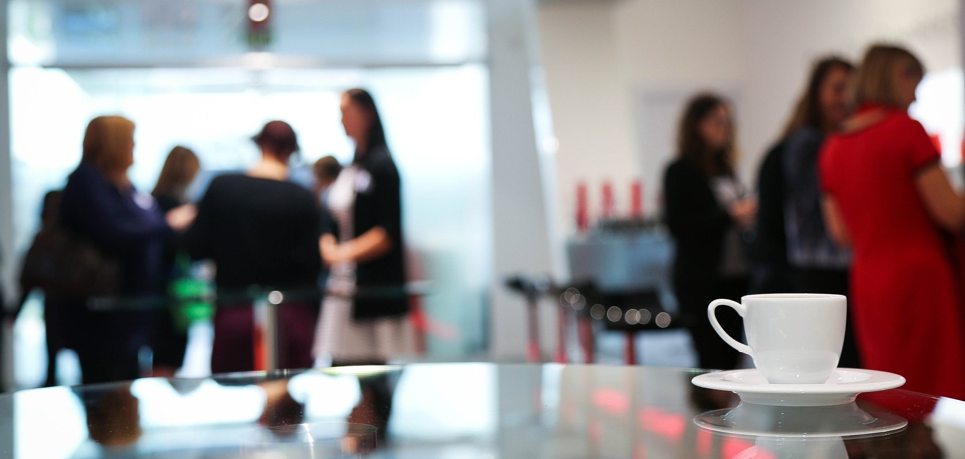 Personen stehen an Stehtischen und unterhalten sich.