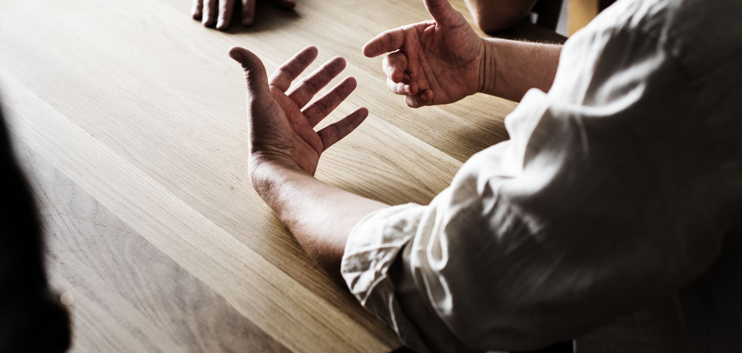 Drei Personen sitzen an einem Tisch und sprechen miteinander.