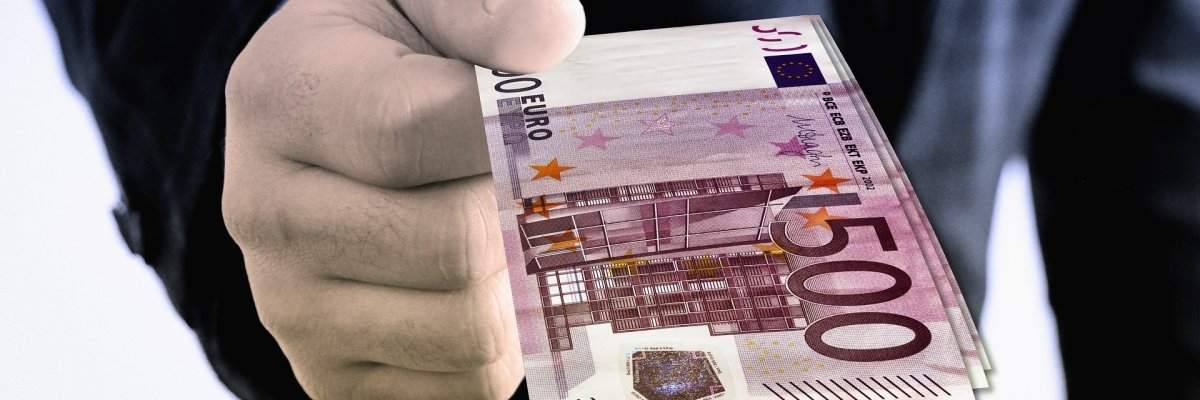 Korruption Eine Hand, die einen 500 Euro-Geldschein in die Kamera reicht.