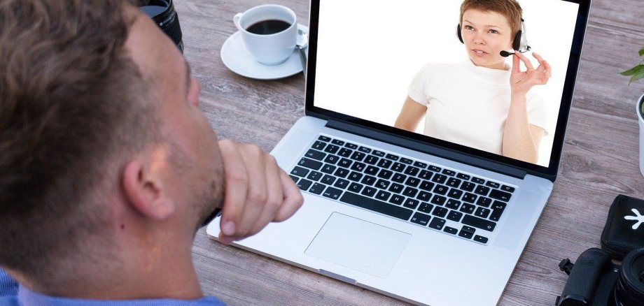 Ein Mann sitzt vor seinem Laptop und verfolgt ein Webinar.