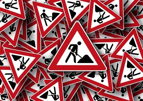 Man sieht ganz viele rotweiße Baustellenschilder mit einem schwarzen Männchen mit Schüppe und Sandhaufen auf einen Haufen.