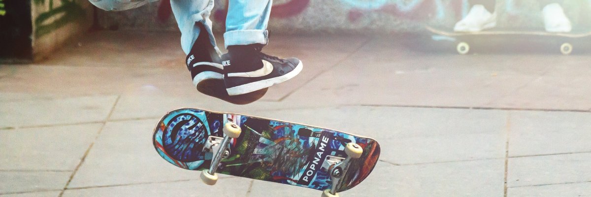 Unterkörper einer Person, die zusammen mit ihrem Skateboard in die Höhe springt