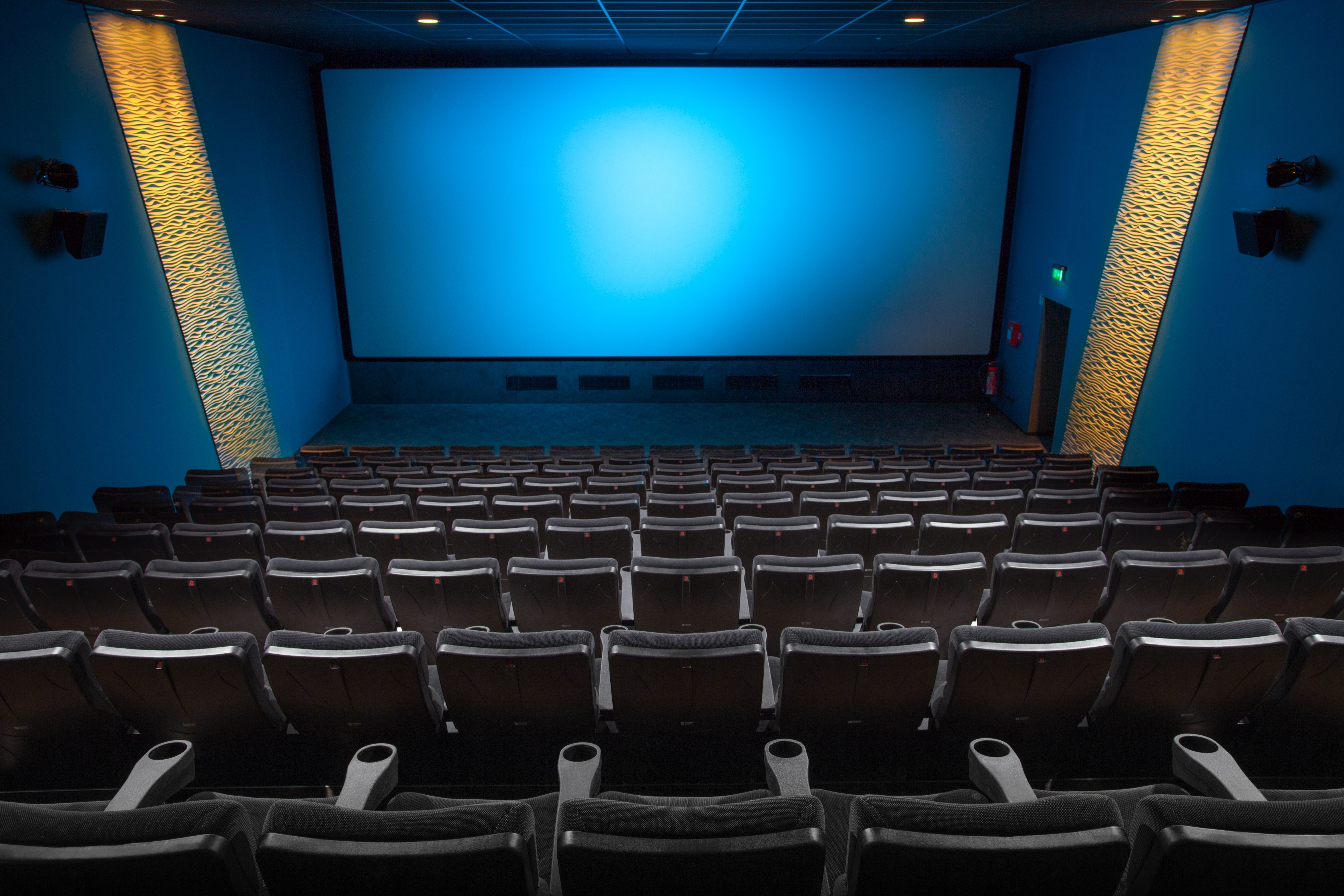 Kinosaal Leerer Kinosaal mit vielen Sitzen und einer großen blauen Leinwand, auf der kein Film spielt.