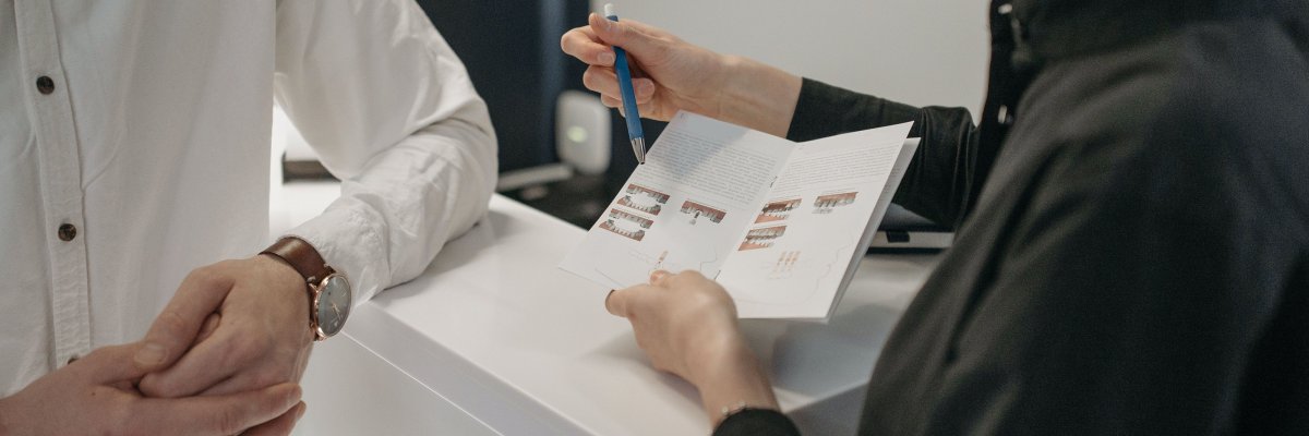 Eine Frau erklärt mit Hilfe eines Flyers einem Mann die Zahnreinigung.