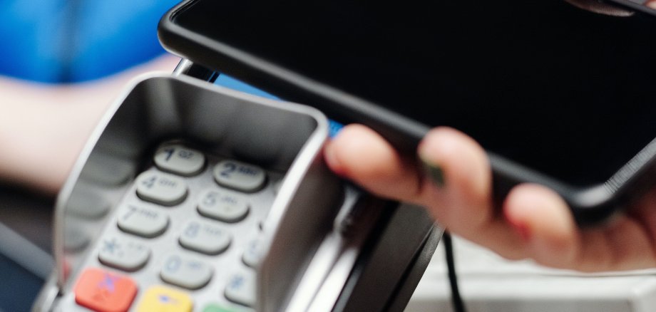 Ein Smartphone wird zur Bezahlung an ein Kartenlesegerät gehalten.