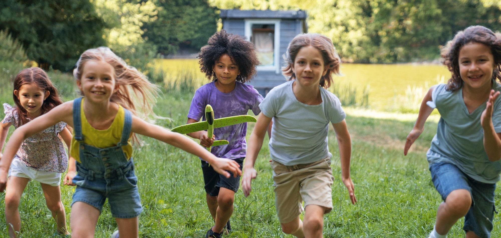 Kinder laufen über eine Wiese.