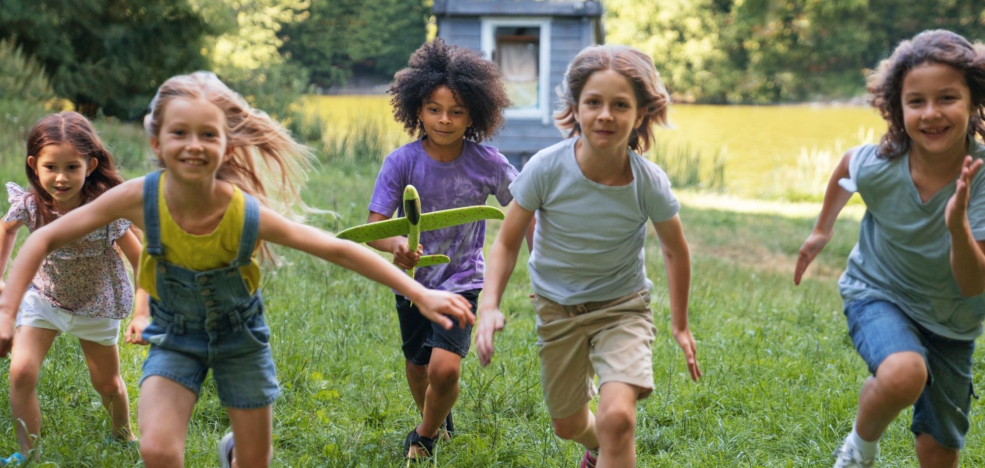 Kinder laufen über eine Wiese.