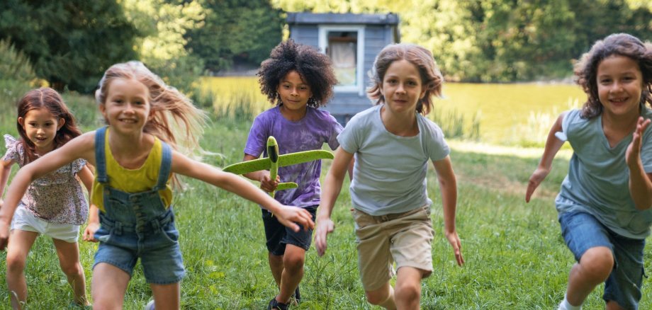 Kinder laufen über eine Wiese.