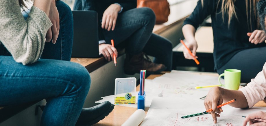 Schülerinnen sitzen um einen Tisch verteilt und besprechen etwas.