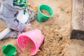 Sandkiste Ein Kind sitzt mit Spielsachen in einer Sandkiste.
