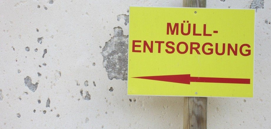 Ein Schild mit der Aufschrift „Müllentsorgung“ und einem Pfeil nach links.