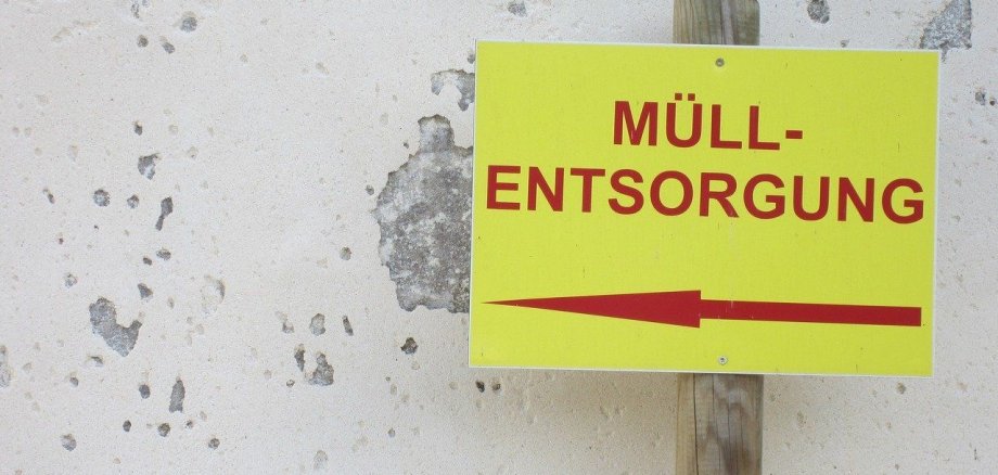 Ein Schild mit der Aufschrift „Müllentsorgung“ und einem Pfeil nach links.