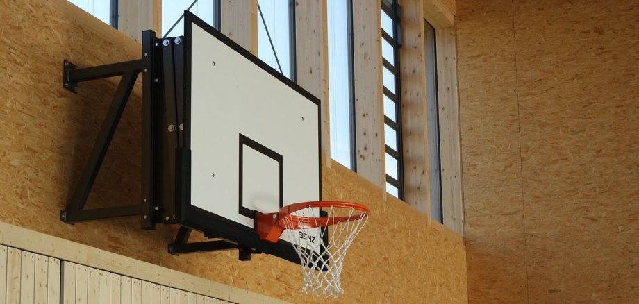 Basketballkorb der an der Wand einer Sporthalle hängt