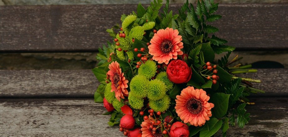 Ein Blumenstrauß liegt auf einem Holzboden.