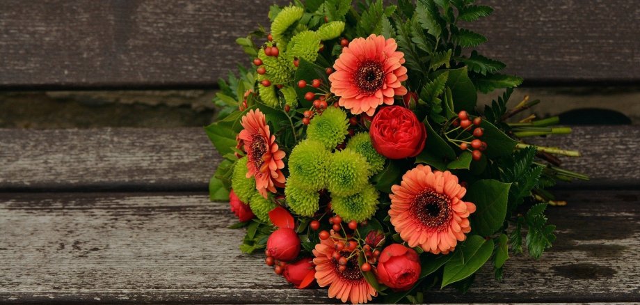 Ein Blumenstrauß liegt auf einem Holzboden.