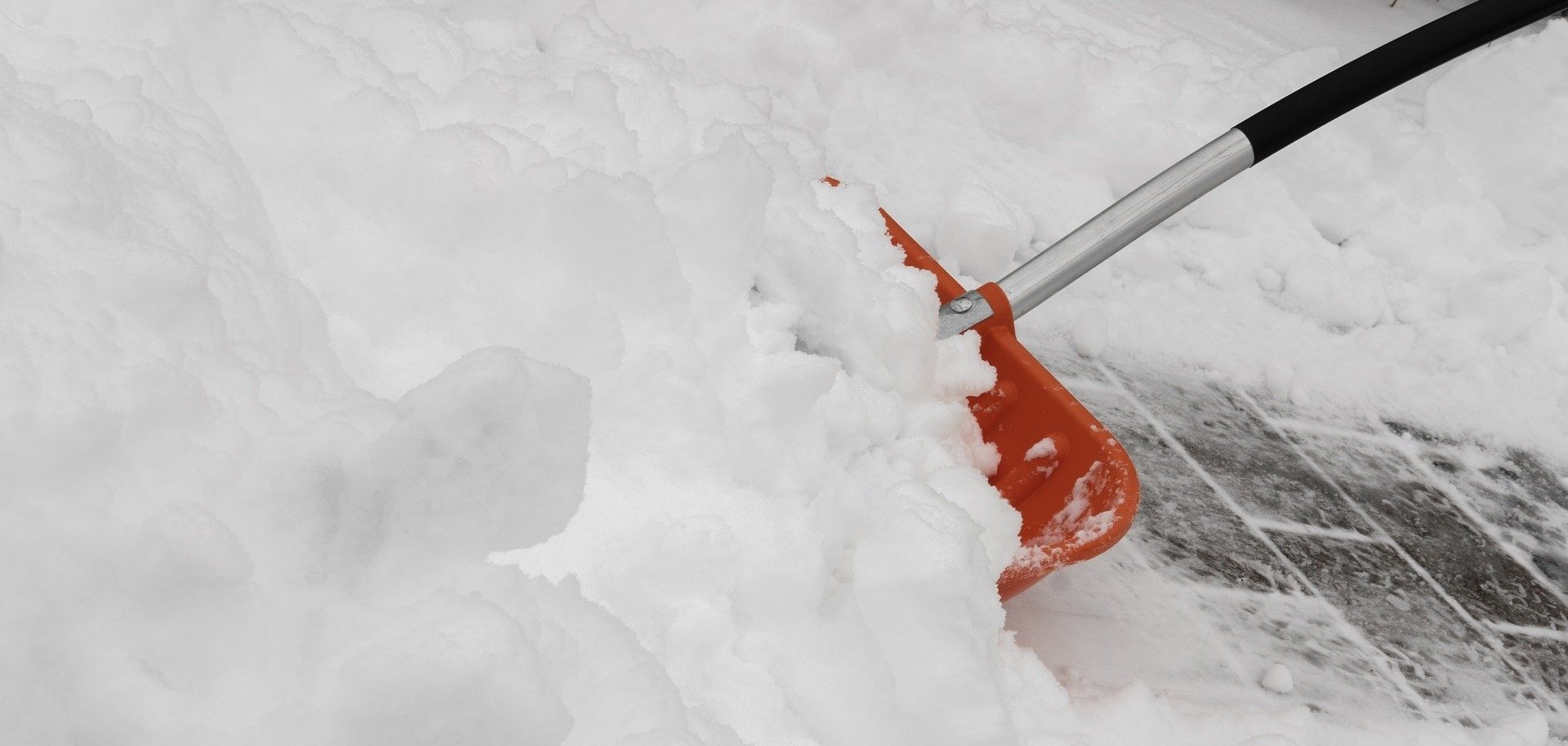 Eine Schaufel zum Schneeschippen steckt im Schnee.