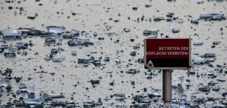 Auf einer zugefrorenen Eisfläche steht das Schild „Betreten der Eisfläche verboten!“.