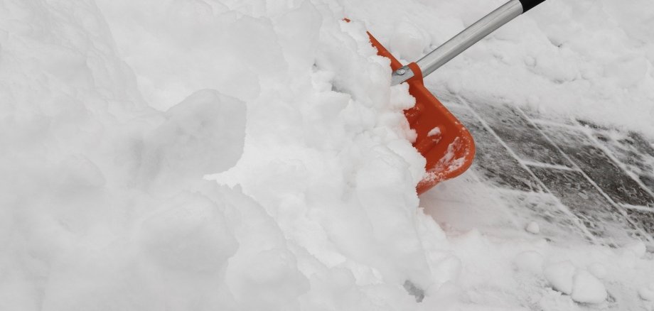 Eine Schaufel zum Schneeschippen steckt im Schnee.