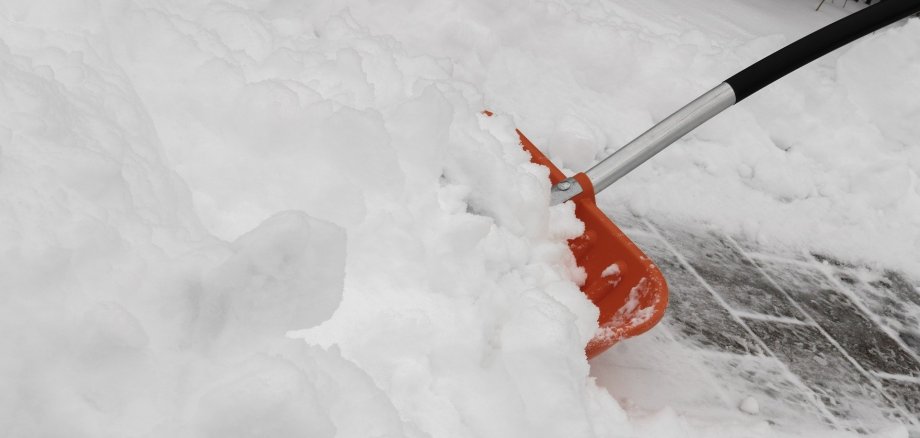 Eine Schaufel zum Schneeschippen steckt im Schnee.