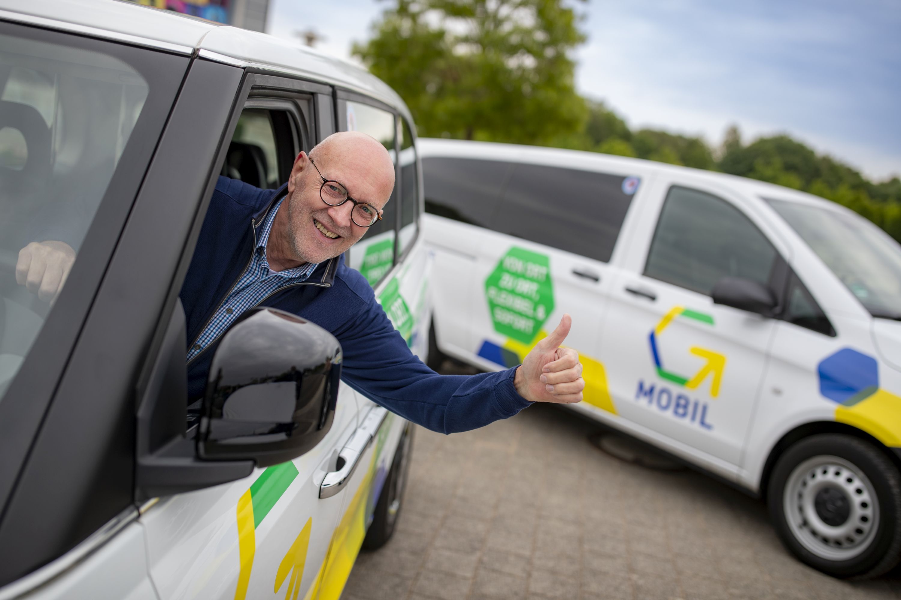 Der Fahrer des G-Mobils streckt seinen Daumen nach oben.