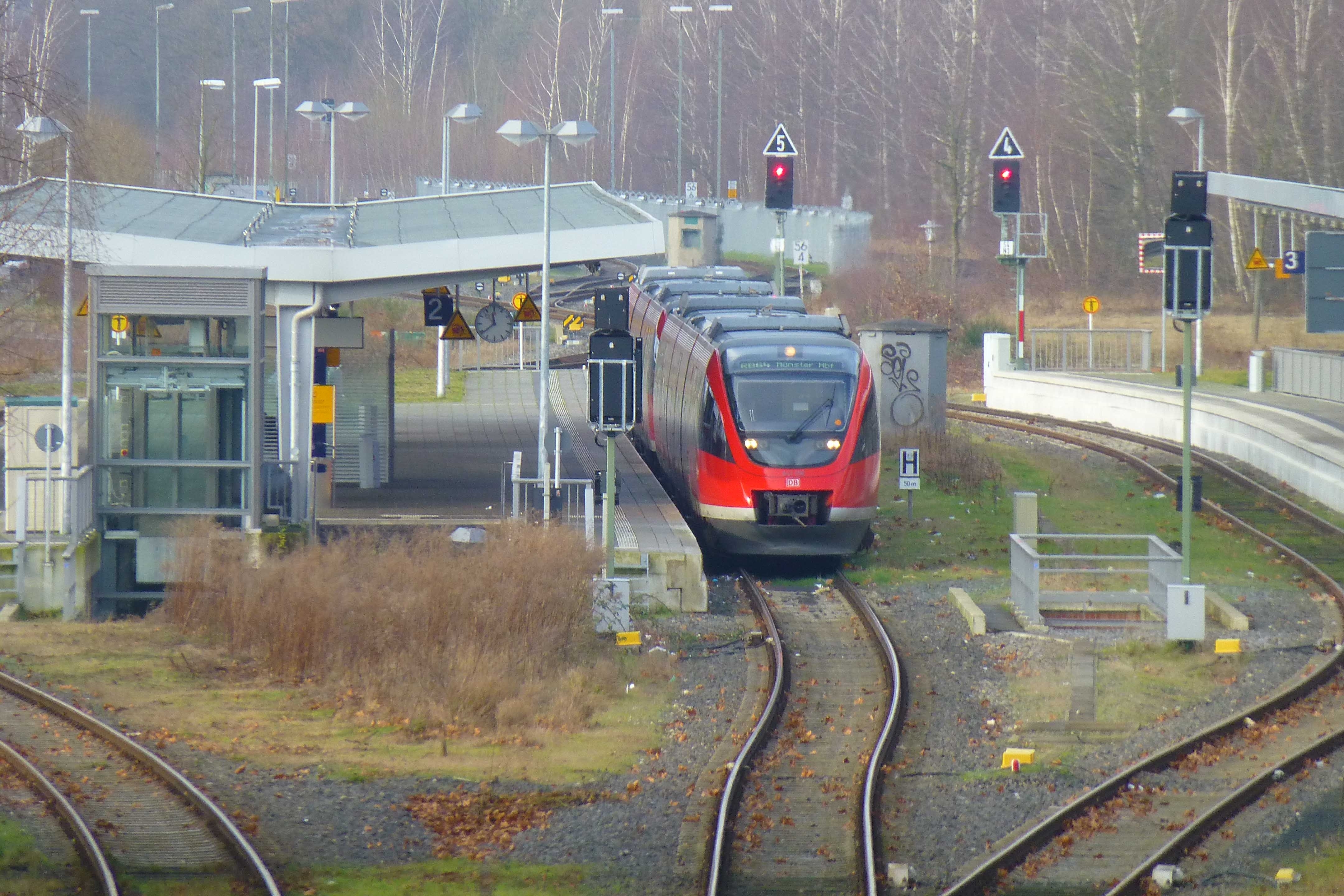 Ein Blick auf die Bahnhofsgleise des Bahnhofes in Gronau. Am Gleis zwei steht ein roter Zug der deutschen Bahn.