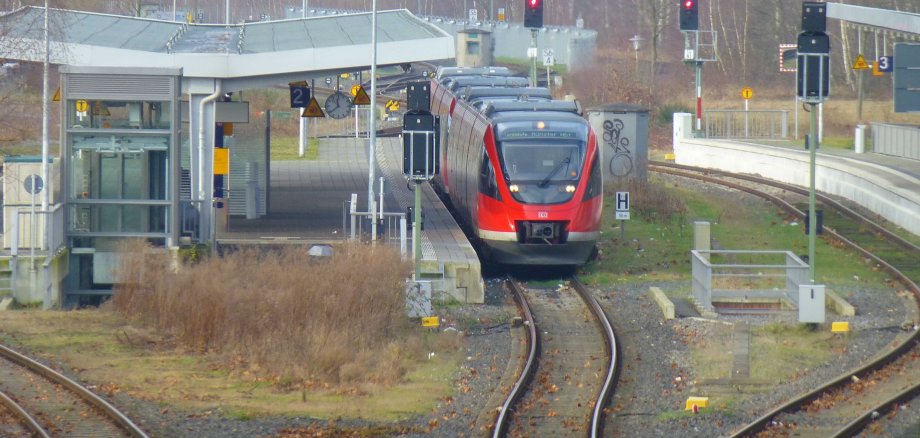 Ein Blick auf die Bahnhofsgleise des Bahnhofes in Gronau. Am Gleis zwei steht ein roter Zug der deutschen Bahn.