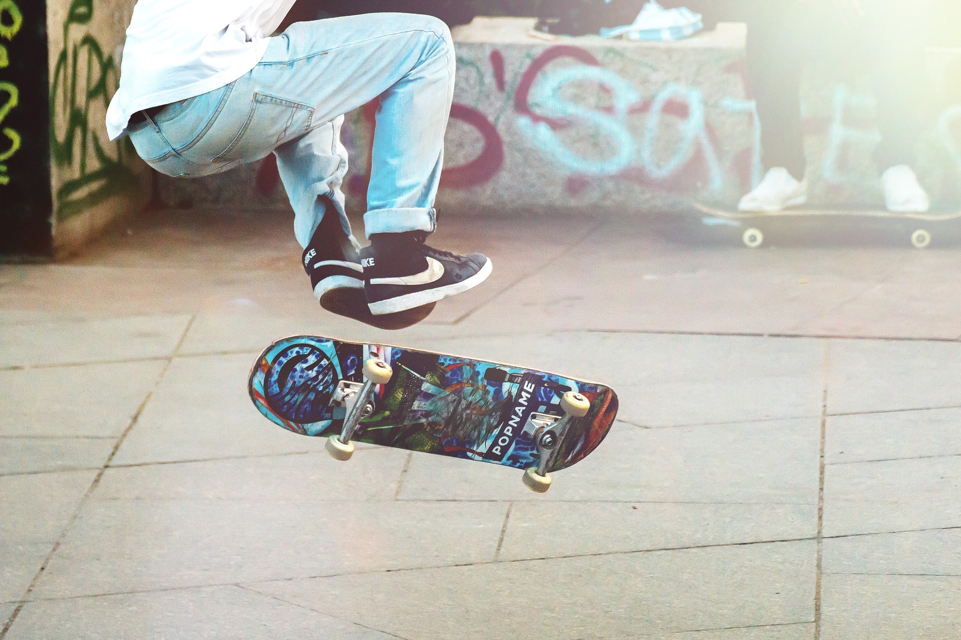Unterkörper einer Person, die zusammen mit ihrem Skateboard in die Lüfte springt.